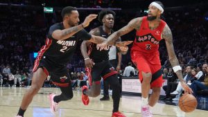 Miami Heat guard Norman Powell, left, and guard Davion Mitchell, center, defend Toronto Raptors forward Brandon Ingram (3) during the second half of an NBA basketball game, Monday, Dec. 15, 2025, in Miami. (AP Photo/Lynne Sladky)