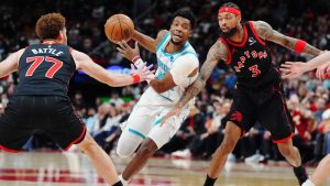 Charlotte Hornets' Brandon Miller (24) drives between Toronto Raptors' Jamison Battle (77) and Brandon Ingram (3) during first half NBA basketball action in Toronto on Friday, Dec. 5, 2025. THE CANADIAN PRESS/Frank Gunn