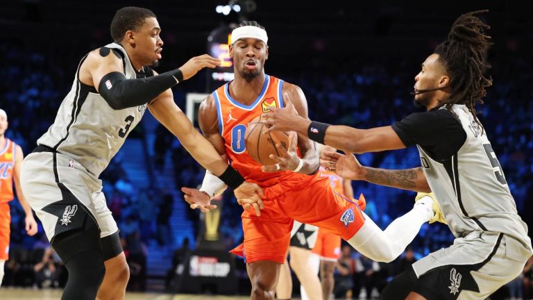 Oklahoma City Thunder guard Shai Gilgeous-Alexander, center, tangles with San Antonio Spurs' Keldon Johnson (3) and Stephon Castle (5) under the net in the first half of an NBA Cup semifinals basketball game, Saturday, Dec. 13, 2025, in Las Vegas. (Ronda Churchill/AP)