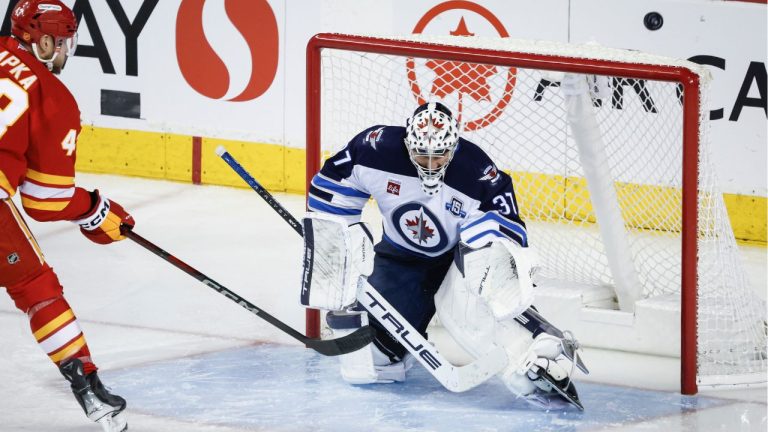Winnipeg Jets goalie Connor Hellebuyck (37) guards the net as Calgary Flames' Adam Klapka shoots wide during second period NHL hockey action in Calgary, Alta., Saturday, Nov. 15, 2025. (Jeff McIntosh/CP)