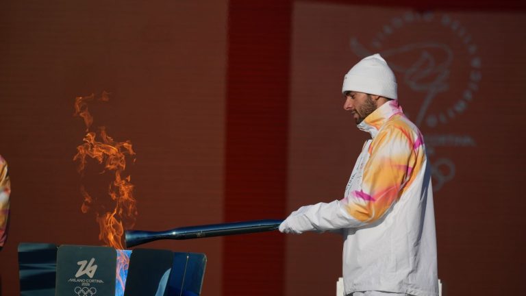Italian swimmer Gregorio Paltrinieri lights the 2026 Milan Cortina Winter Olympics torch in Rome as it begins its journey through Italy, Saturday, Dec. 6, 2025, a journey that will conclude in Milan in February 2026. (Andrew Medichini/AP)