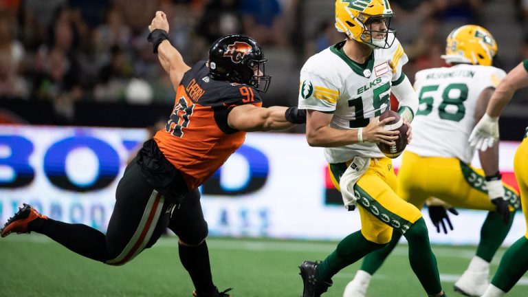 Edmonton Elks quarterback Taylor Cornelius (15) gets away from B.C. Lions' Nathan Cherry (91) as he reaches for him during the second half of CFL football game in Vancouver, on Saturday, August 6, 2022. (Darryl Dyck/CP)