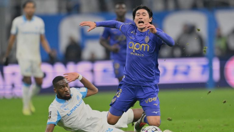 Monaco's Takumi Minamino, right, reacts as he challenges with Marseille's Geoffrey Kondogbia during the French League One soccer match between Marseille and Monaco in Marseille, France, Sunday, Dec. 14, 2025. (Philippe Magoni/AP)