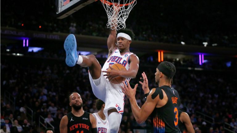 Philadelphia 76ers guard VJ Edgecombe, centre, holds the ball after dunking over New York Knicks guards Jalen Brunson, left, and Josh Hart, right, during the second half of an NBA basketball game, Friday, Dec. 19, 2025, in New York. (John Munson/AP)