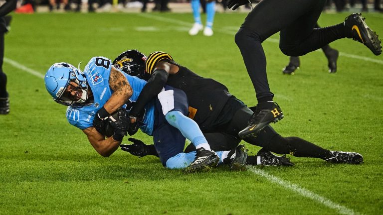 Toronto Argonauts wide receiver David Ungerer (83) is tackled by Hamilton Tiger-Cats defensive back Jamal Peters (2) during CFL action in Toronto, on Friday, July 4, 2025. (Sammy Kogan/CP)
