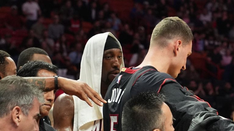 Miami Heat forward Nikola Jovic, right, helped off the court during the first half of a game against the Toronto Raptors, Monday, Dec. 15, 2025, in Miami. (AP Photo/Lynne Sladky)