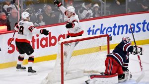 Ottawa Senators' Brady Tkachuk (7) celebrates his game-winning goal in overtime against Winnipeg Jets' goaltender Connor Hellebuyck (37) with Tim Stulzle (18) during their game in Winnipeg, Monday, Dec. 15, 2025. (Fred Greenslade/CP)