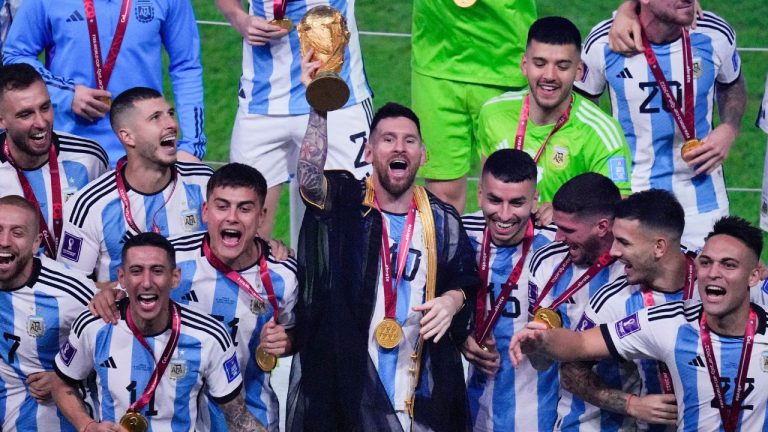 Argentina's Lionel Messi holds the trophy aloft as he celebrates with his team at the end of the World Cup final soccer match between Argentina and France at the Lusail Stadium in Lusail, Qatar, Sunday, Dec. 18, 2022. (Hassan Ammar/AP)