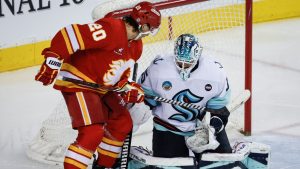 Seattle Kraken goalie Joey Daccord, right, blocks the net on Calgary Flames' Blake Coleman during third period NHL hockey action in Calgary on Saturday, Feb. 8, 2025. (Jeff McIntosh/THE CANADIAN PRESS)