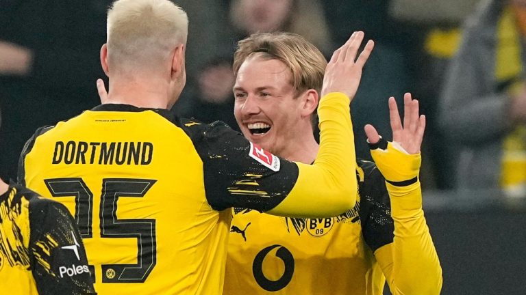 Dortmund's Julian Brandt, right, celebrates with Dortmund's Niklas Suele, left, during the Bundesliga match between Borussia Dortmund and Borussia Moenchengladbach in Dortmund, Germany, Friday, Dec. 19, 2025. (AP Photo/Martin Meissner)