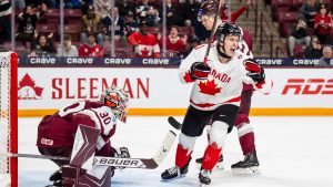Canada's Cole Reschny (21) celebrates in front of Latvia goaltender Nils Maurins (30) after Canada defeated Latvia in overtime IIHF World Junior Championship hockey action, in Minneapolis, Saturday, Dec. 27, 2025. (Christopher Katsarov/CP)