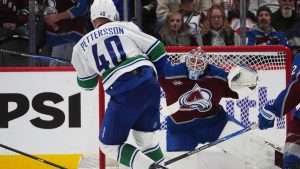 Colorado Avalanche goaltender Mackenzie Blackwood, back, stops a shot from Vancouver Canucks centre Elias Pettersson in the third period of an NHL hockey game Tuesday, Dec. 2, 2025, in Denver. (David Zalubowski/AP)