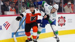 Philadelphia Flyers' Bobby Brink, left, and Vancouver Canucks' Zeev Buium battle along the boards during the second period of an NHL hockey game, Monday, Dec. 22, 2025, in Philadelphia. (Derik Hamilton/AP)