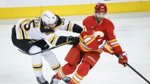 Boston Bruins' Justin Brazeau, left, checks Calgary Flames' Nazem Kadri during first period NHL hockey action in Calgary on Tuesday, Dec. 17, 2024. (Jeff McIntosh/CP)
