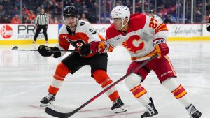 Calgary Flames' Matt Coronato (27) and Philadelphia Flyers' Jamie Drysdale (9) race for the puck during the third period of an NHL hockey game, Sunday, Nov. 2, 2025, in Philadelphia. (Derik Hamilton/AP)