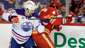 Edmonton Oilers' Max Jones (46) checks Calgary Flames' Rasmus Andersson during first period NHL hockey action in Calgary, Alta., Saturday, Dec. 27, 2025. (Jeff McIntosh/CP)