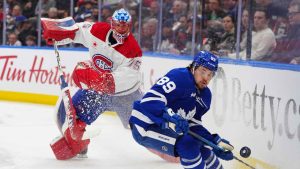 Montréal Canadiens goaltender Jakub Dobes (75) moves the puck along the boards behind the net as Toronto Maple Leafs left wing Nicholas Robertson (89) tries to track it down during second period NHL hockey action. (Frank Gunn/The Canadian Press)