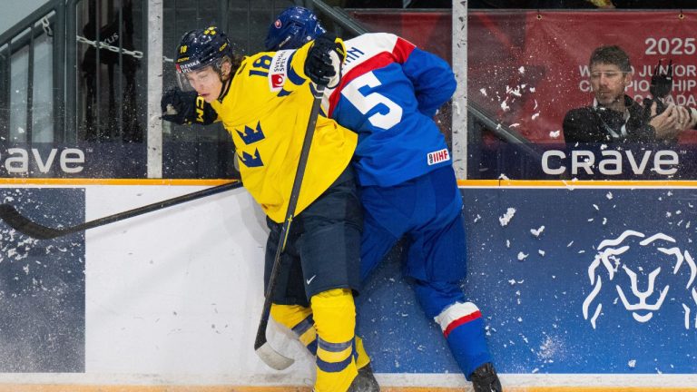 Sweden forward Victor Eklund (18) checks Slovakia's Richard Baran (5) into the boards during first period IIHF World Junior Hockey Championship preliminary round action in Ottawa, Thursday, Dec. 26, 2024. (Spencer Colby/THE CANADIAN PRESS)