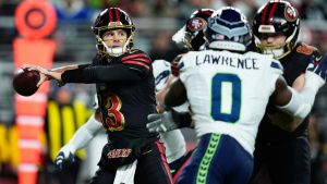 San Francisco 49ers quarterback Brock Purdy (13) passes as Seattle Seahawks linebacker DeMarcus Lawrence (0) applies pressure during the first half of an NFL football game in Santa Clara, Calif., Saturday, Jan. 3, 2026. (AP Photo/Godofredo A. Vásquez)