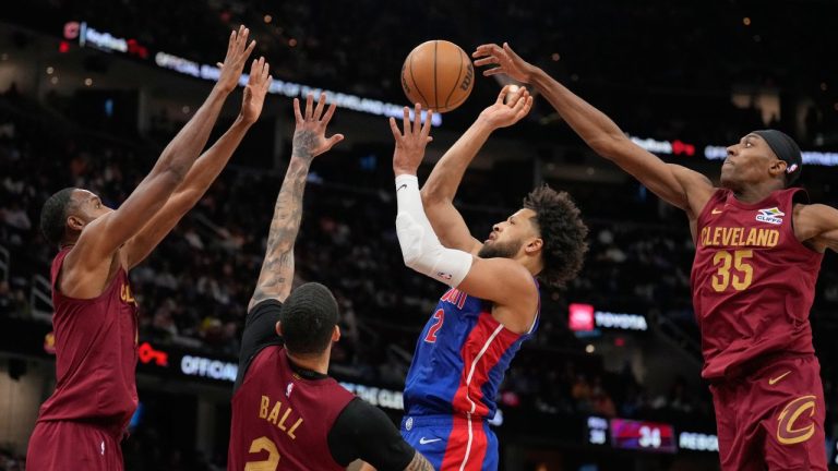 Detroit Pistons guard Cade Cunningham, center, shoots between Cleveland Cavaliers center Evan Mobley, left, guard Lonzo Ball (2) and forward Nae'qwan Tomlin (35) in the second half of an NBA basketball game Sunday, Jan. 4, 2026, in Cleveland. (AP Photo/Sue Ogrocki)