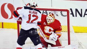 New Jersey Devils' Cody Glass, left, has a shot stopped by Calgary Flames goalie Devin Cooley during first period NHL hockey action in Calgary, Alta., Monday, Jan. 19, 2026. (Larry MacDougal/CP)