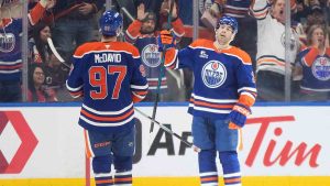 Washington Capitals' Aliaksei Protas (21) skates past as Edmonton Oilers' Connor McDavid (97) and Evan Bouchard (2) celebrate a goal during third period NHL action, in Edmonton on Saturday, Jan. 24, 2026. (Jason Franson/CP)