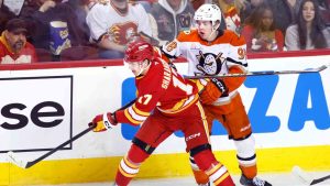 Anaheim Ducks' Pavel Mintyukov (98) and Calgary Flames' Yegor Sharangovich vie for control of the puck during first period NHL hockey action in Calgary, Alta., Sunday, Jan. 25, 2026. (Larry MacDougal/CP)