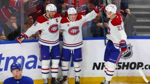 Montréal Canadiens right wing Cole Caufield (13), centre, celebrates his goal with centre Nick Suzuki (14), left, and defenceman Kaiden Guhle (21),right, during the third period of an NHL hockey game against the Buffalo Sabres Saturday, Jan. 31, 2026, in Buffalo, N.Y. (Jeffrey T. Barnes/AP)