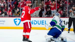 Detroit Red Wings left wing J.T. Compher, left, reacts near Vancouver Canucks goaltender Kevin Lankinen, front right, after scoring during the second period of an NHL hockey game Thursday, Jan. 8, 2026, in Detroit. (Ryan Sun/AP)