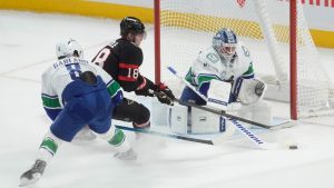 Vancouver Canucks goaltender Kevin Lankinen (32) poke checks the puck away from Ottawa Senators centre Tim Stutzle (18) as he is pressured by Canucks right wing Conor Garland (8) during second period NHL action in Ottawa, Tuesday, Jan. 13, 2026. THE CANADIAN PRESS/Adrian Wyld
