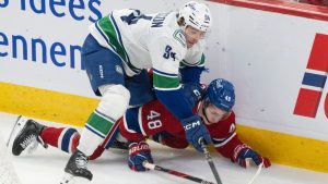 Vancouver Canucks' Linus Karlsson (94) and Montreal Canadiens' Lane Hutson (48) battle for the puck during first period NHL hockey action in Montreal on Monday, Jan. 12, 2026. (Christinne Muschi/CP)