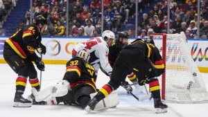 Washington Capitals' Justin Sourdif (34) scores against Vancouver Canucks goalie Kevin Lankinen (32) as Filip Hronek (17), David Kampf (64) and defenceman Elias Pettersson, front right, defend during the first period of an NHL hockey game, in Vancouver, on Wednesday, January 21, 2026. (Darryl Dyck/CP)