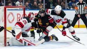 New Jersey Devils goaltender Jacob Markstrom (25) stops Vancouver Canucks' Jake Debrusk (74) as New Jersey's Brenden Dillon (5) watches during the third period of an NHL hockey game in Vancouver, on Friday, January 23, 2026. (Ethan Cairns/CP)
