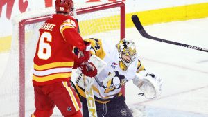 Pittsburgh Penguins goalie Stuart Skinner makes a save as Calgary Flames' Joel Farabee looks for a rebound during first period NHL hockey action in Calgary, Wednesday, Jan. 21, 2026. (Larry MacDougal/CP)