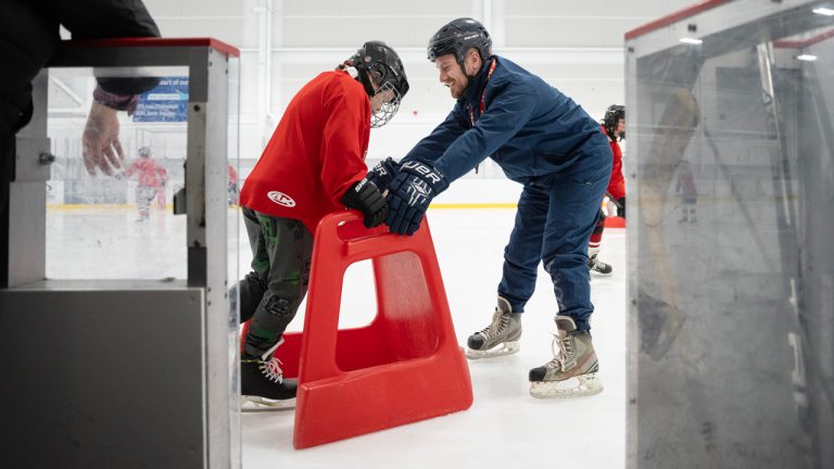 Skate Your Way coach Ryan Camp, right, helps teach a participant to skate in Dieppe, N.B. on Sat., January 10, 2026. (Photo by Darren Calabrese/Sportsnet)