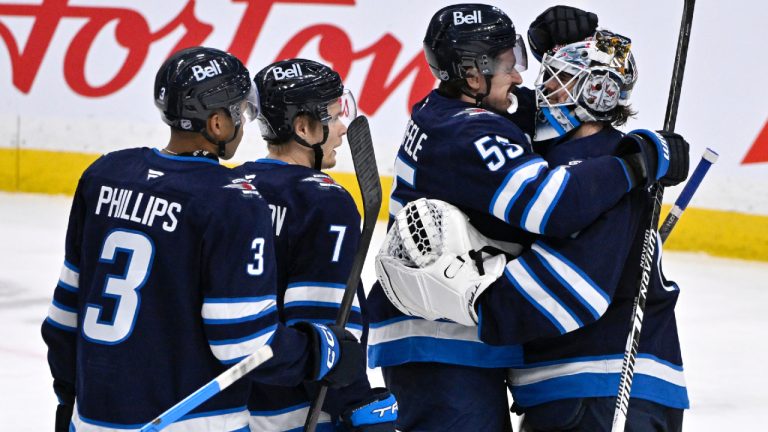 Winnipeg Jets' goaltender Eric Comrie (1) celebrates the win over the St. Louis Blues with Mark Scheifele (55) following their NHL hockey game in Winnipeg, Tuesday January 20, 2026. (Fred Greenslade/CP)