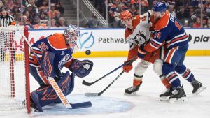 Anaheim Ducks' Beckett Sennecke (45) and Edmonton Oilers' Mattias Ekholm (14) battle in front of as goalie Tristan Jarry (35) makes the save during first period NHL action, in Edmonton on Monday, Jan. 26, 2026. (Jason Franson/CP)