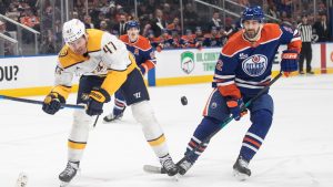 Nashville Predators' Michael McCarron (47) and Edmonton Oilers' Evan Bouchard (2) battle for the puck during first period NHL action, in Edmonton on Tuesday, January 6, 2026. THE CANADIAN PRESS/Jason Franson