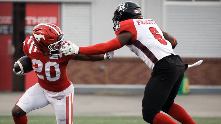Ottawa Redblacks' Adarius Pickett (6) grabs the face mask of Calgary Stampeders' Peyton Logan (20) during first half CFL football action in Calgary, Thursday, Aug. 15, 2024. (Jeff McIntosh/CP)
