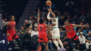 Charlotte Hornets guard Lamelo Ball (1) shoots the ball against Toronto Raptors guard Immanuel Quickley (5), Toronto Raptors forward Collin Murray-Boyles (12) , left, and Toronto Raptors forward/guard RJ Barrett (9), right, during the first half of an NBA basketball game on Wednesday, Jan. 7, 2026, in Charlotte, N.C. (AP Photo/Krista Jasso)