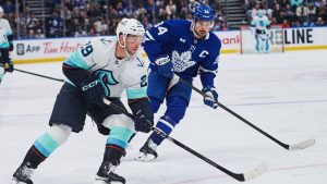 Seattle Kraken's Vince Dunn (29) and Toronto Maple Leafs' Auston Matthews (34) battle for the puck during third period NHL hockey action in Toronto, on Saturday, Oct. 18, 2025. (Sammy Kogan/CP)