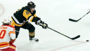 Pittsburgh Penguins' Sidney Crosby (87) reaches for the puck next to Calgary Flames' Blake Coleman (20) during the third period of an NHL game Saturday, Nov. 30, 2024, in Pittsburgh. (AP Photo/Matt Freed)