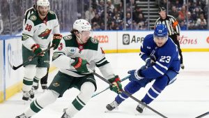 Minnesota Wild defenceman Quinn Hughes (43) and Toronto Maple Leafs forward Matthew Knies (23) vie for control of the puck during first period NHL hockey action in Toronto, Monday, Jan. 19, 2026. (Nathan Denette/CP)