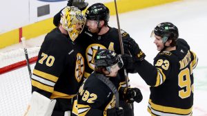 Boston Bruins goaltender Joonas Korpisalo (70) with centers Elias Lindholm (28), Marat Khusnutdinov (92) and Fraser Minten (93) celebrate after their team's win over the Pittsburgh Penguins in an NHL hockey game Sunday, Jan. 11, 2026, in Boston. (Mark Stockwell/AP)