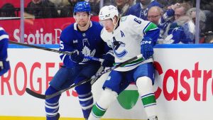 Toronto Maple Leafs' Brandon Carlo (25) and Vancouver Canucks' Brock Boeser (6) battle for the puck during first period NHL hockey action in Toronto on Saturday, Jan. 10, 2026. (Frank Gunn/CP)