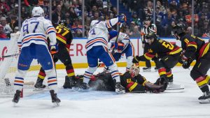 Vancouver Canucks goalie Nikita Tolopilo (60) lies on the ice as Tyler Myers (57) prevents Edmonton Oilers' Zach Hyman (18) from scoring as Connor McDavid (97), Ryan Nugent-Hopkins (93) and Vancouver's Aatu Raty (54) and Conor Garland (8) watch during the second period of an NHL hockey game, in Vancouver. (Darryl Dyck/THE CANADIAN PRESS)