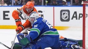 Vancouver Canucks goalie Nikita Tolopilo (60) stops Anaheim Ducks' Ryan Poehling (25) as Poehling crashes into him during the first period of an NHL hockey game, in Vancouver, on Thursday, January 29, 2026. (Darryl Dyck/CP)