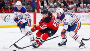 New Jersey Devils centre Jack Hughes (86) plays the puck against Edmonton Oilers defenceman Ty Emberson (49) and centre Ryan Nugent-Hopkins (93) during the second period of an NHL hockey game, Saturday, Oct. 18, 2025, in Newark, N.J. (Noah K. Murray/AP)