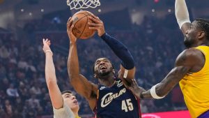 Cleveland Cavaliers guard Donovan Mitchell (45) shoots between Los Angeles Lakers forward Jake LaRavia, left, and centre Deandre Ayton, right, in the first half of an NBA basketball game in Cleveland, Wednesday, Jan. 28, 2026. (Sue Ogrocki/AP)