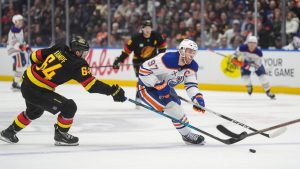 Edmonton Oilers' Connor McDavid (97) skates with the puck past Vancouver Canucks' David Kampf (64) during the first period of an NHL hockey game in Vancouver, on Saturday, Jan. 17, 2026. (Darryl Dyck/CP)